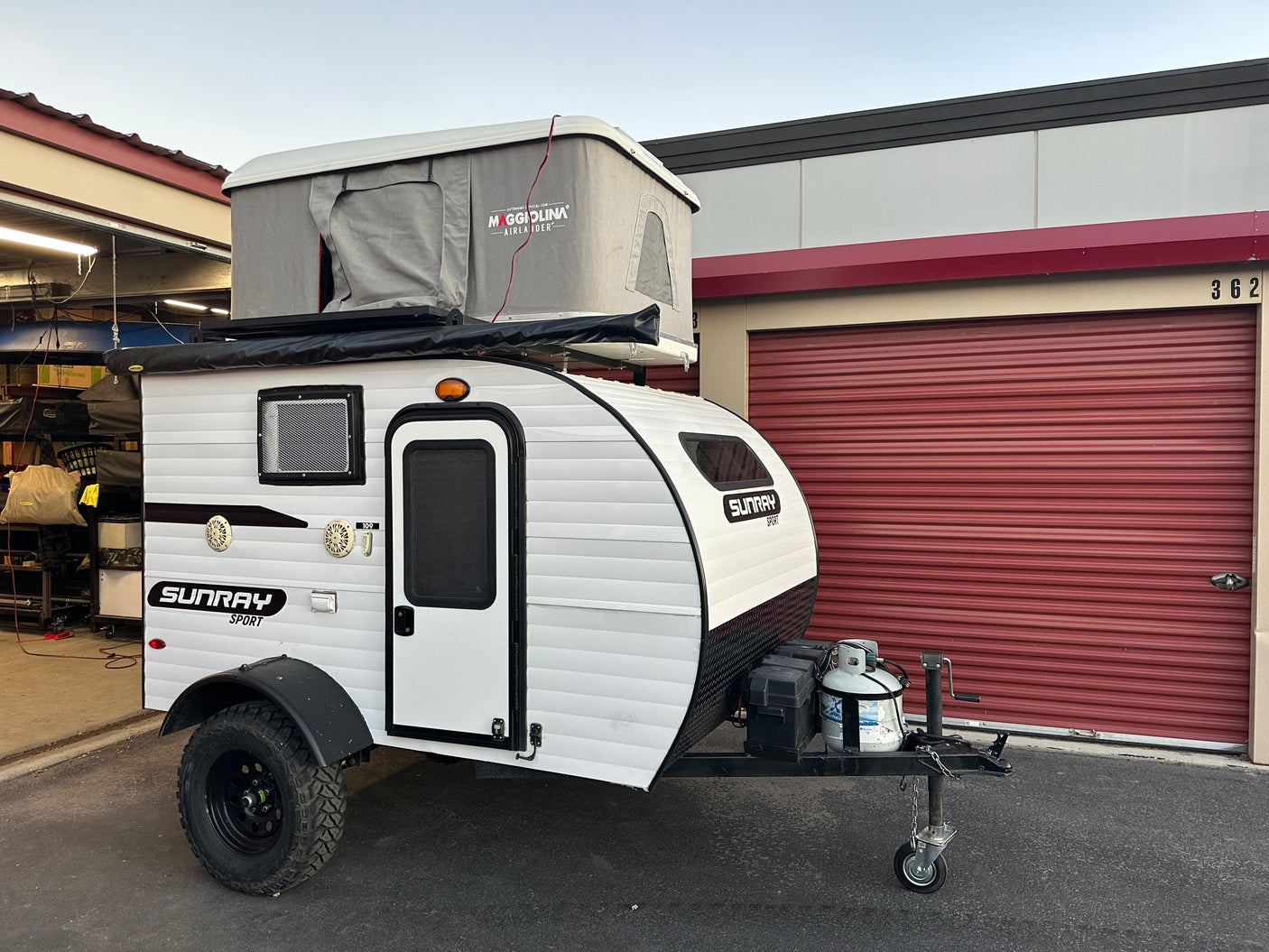 Explore with this white Sunray Sport teardrop camper, featuring a Maggiolina rooftop tent – perfect for an RV rental adventure!