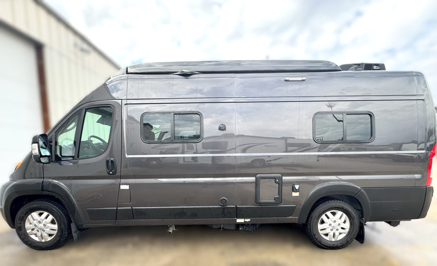 Side view of a sleek gray camper van, ideal for RV rental. Features include a raised roof, side windows, and a rooftop AC unit.