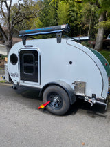This white teardrop camper, great for an RV rental, features a rooftop road shower for comfortable outdoor camping.