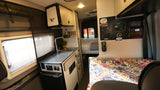 Inside a modern RV rental: compact kitchen, multi-functional control panel, and cozy sleeping area for adventurers.
