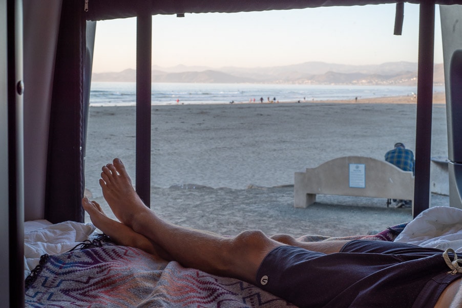Enjoying an RV rental. Feet up, looking out the window at a sandy beach, ocean, and distant mountains. A serene view. — photo 8