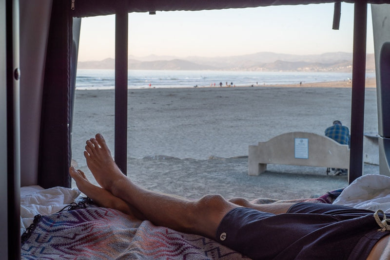 Enjoying an RV rental. Feet up, looking out the window at a sandy beach, ocean, and distant mountains. A serene view. — photo 8