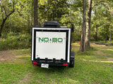 White NO BO camper trailer for RV rental adventures, parked in a lush, green forest campsite in Louisiana.