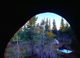 Sunrise from a tent at a peaceful forest campsite, another tent and gear seen. Perfect for your next rv rental adventure!