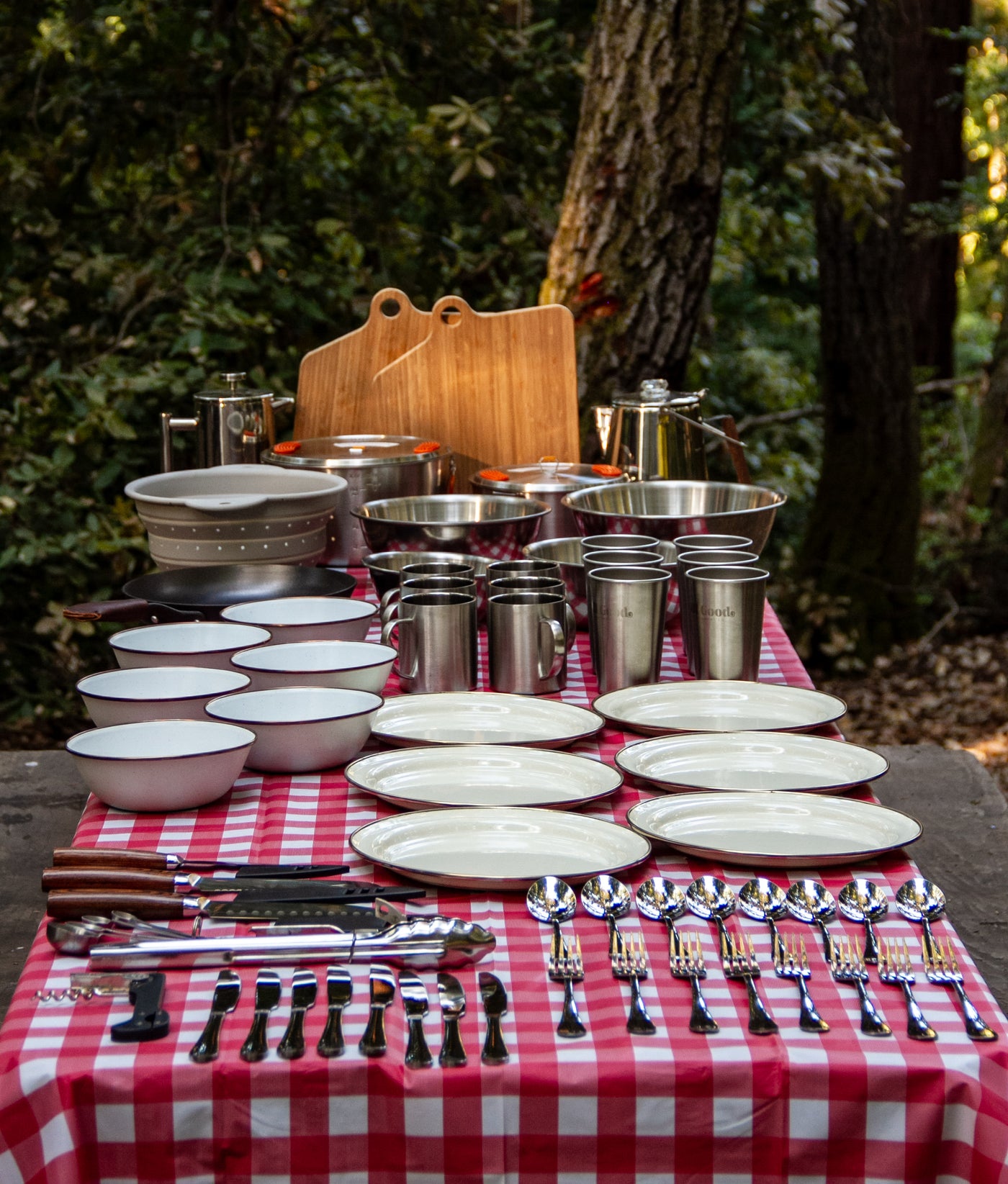 Complete outdoor cooking & dining gear for your RV rental trip: pots, plates, mugs, & utensils on a checkered picnic table. — photo 3