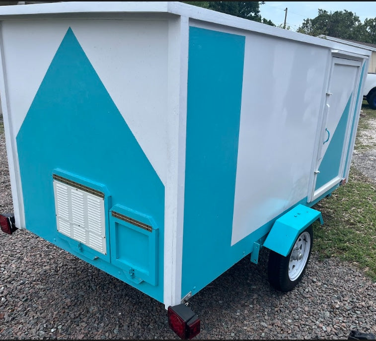 This custom-built teal & white small trailer, resembling a tiny house, ready for an RV rental. Features rear access.