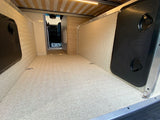 Spacious RV rental cargo area with textured floor, side storage, and convertible bed above, great for gear.