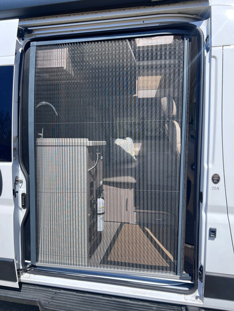 RV rental's open side door with a pleated screen, revealing an interior sink and fire extinguisher inside the camper van.