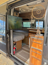 Cozy rv rental interior with beds, TV, kitchen, and dreamcatchers, ready for adventure by the ocean.