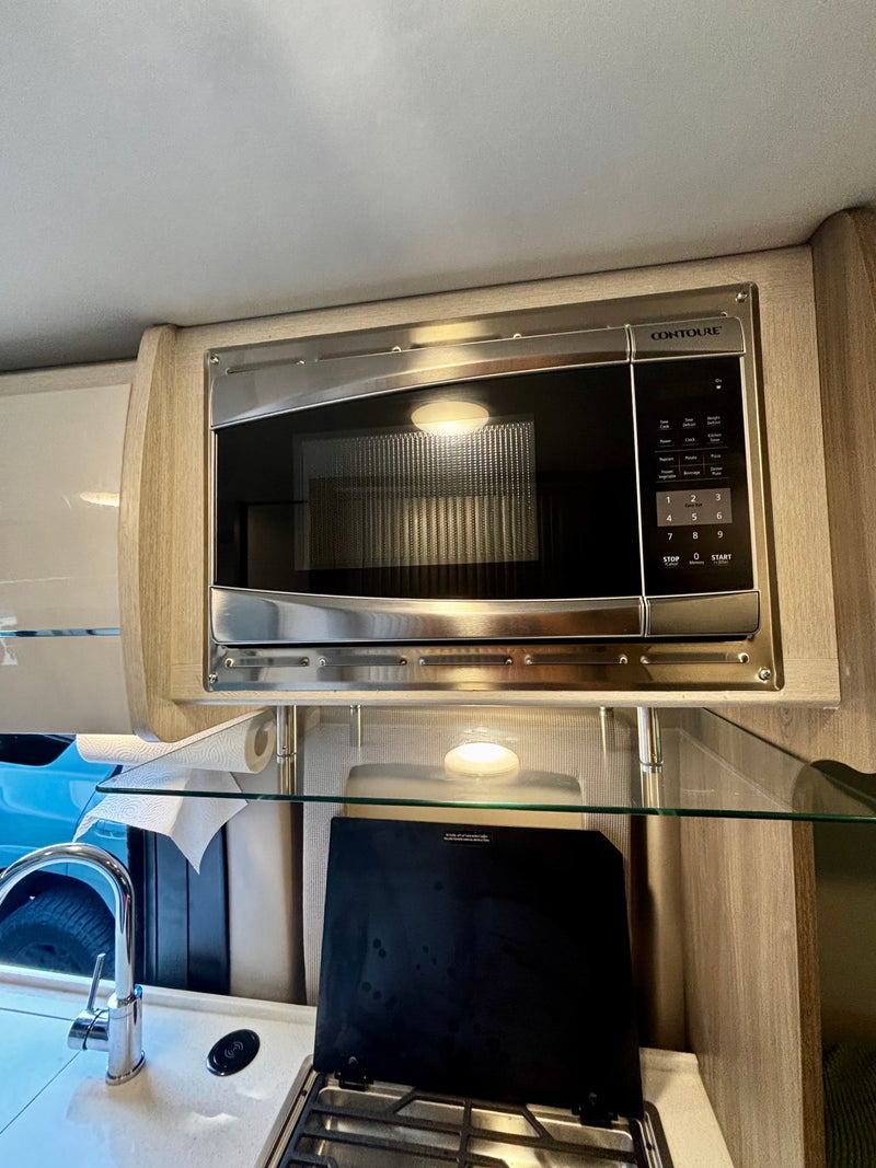 An RV rental kitchen features a Contoure microwave, sink, and stovetop for convenient cooking on your trip. — photo 20