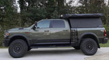 Olive green Ram Power Wagon with a truck camper and awning, an ideal RV rental for overlanding adventures.