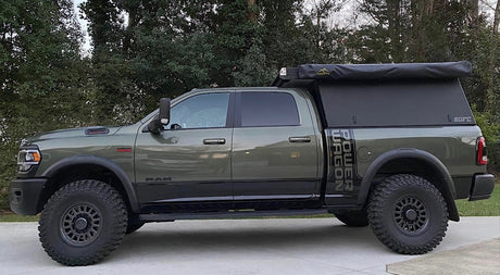 Olive green Ram Power Wagon with a truck camper and awning, an ideal RV rental for overlanding adventures.