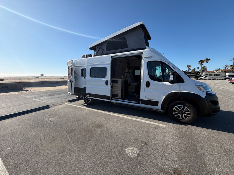 with a cozy campfire & Joshua trees.|White pop-top camper van rv rental at a sunny beach. Doors are open — photo 2