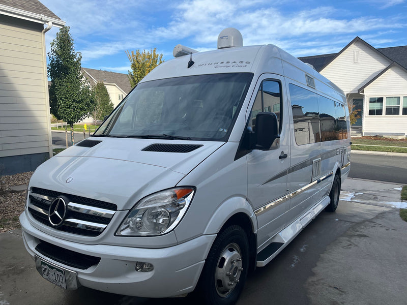 A white Mercedes-Benz Sprinter RV rental van, labeled "Winnebago Touring Coach," is parked on a sunny suburban driveway. — photo 2