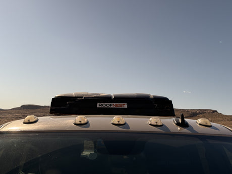 This RV rental with a ROOFNEST rooftop tent is ready for desert adventures under a clear sky.