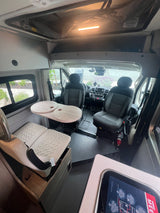 Spacious RV rental interior with a cozy dining area, swivel seats, and ample storage, perfect for travel comfort.