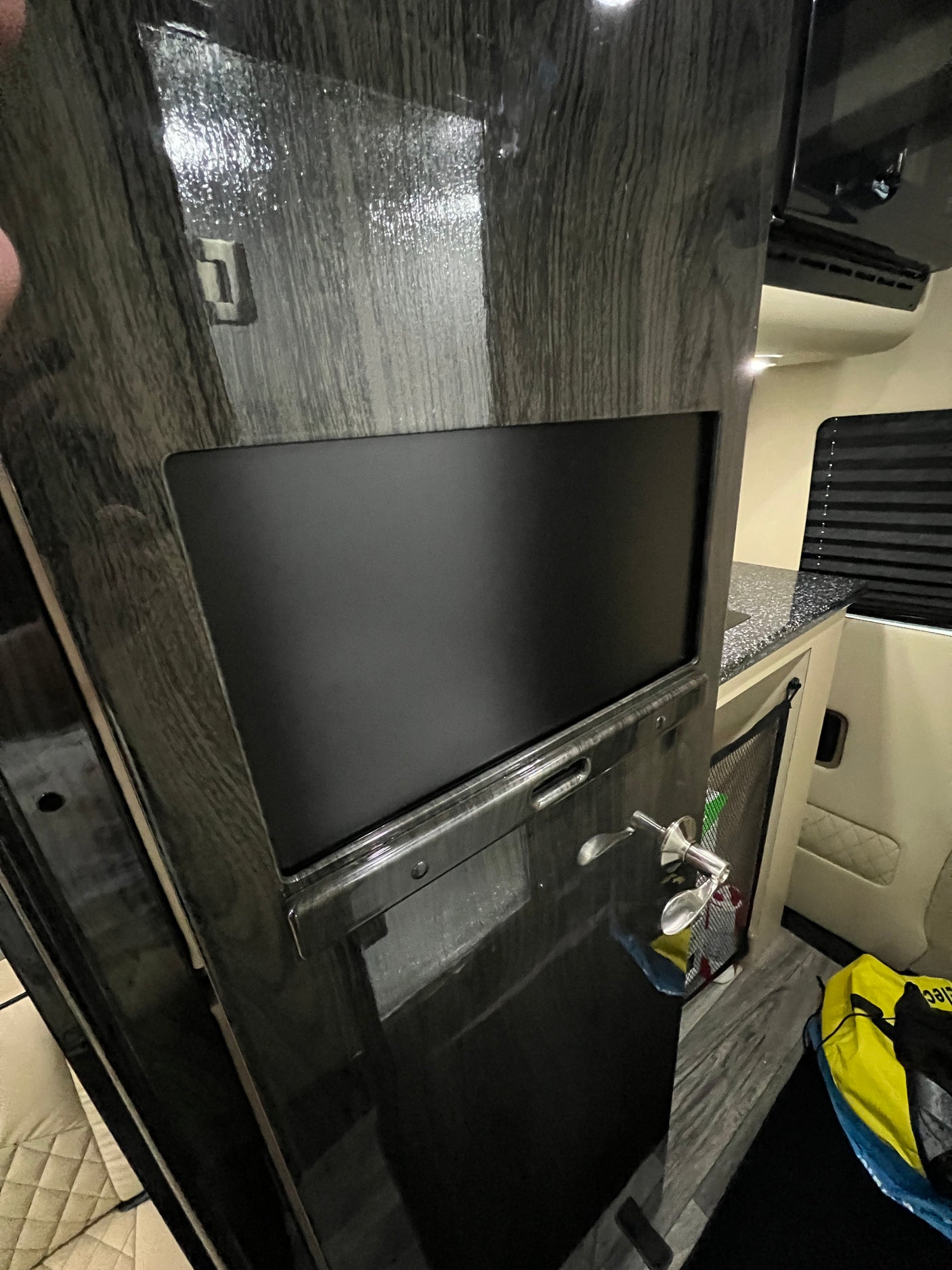 Modern RV rental interior featuring a built-in entertainment screen, sleek cabinetry, and a compact kitchen counter.