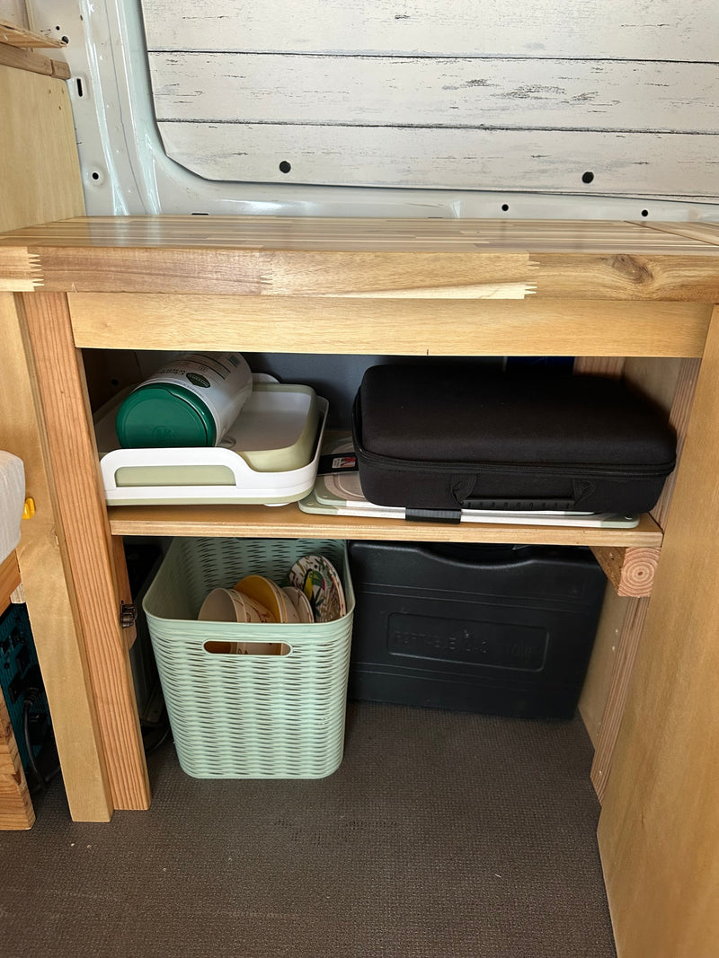 RV rental: compact kitchen cabinet for organized essentials. Features dish rack, dishes, and portable stove. — photo 8