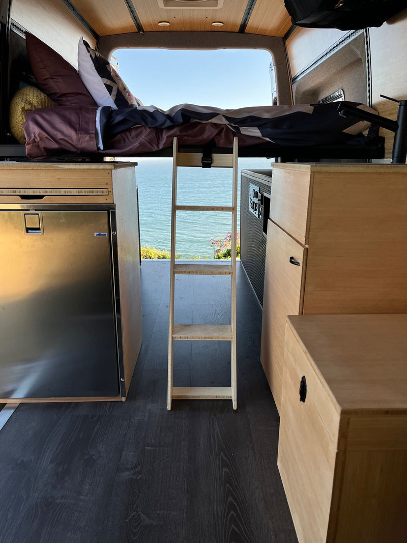 Cozy RV rental interior with elevated bed, Jothrem fridge, and stunning ocean view. Perfect for van life adventures! — photo 12