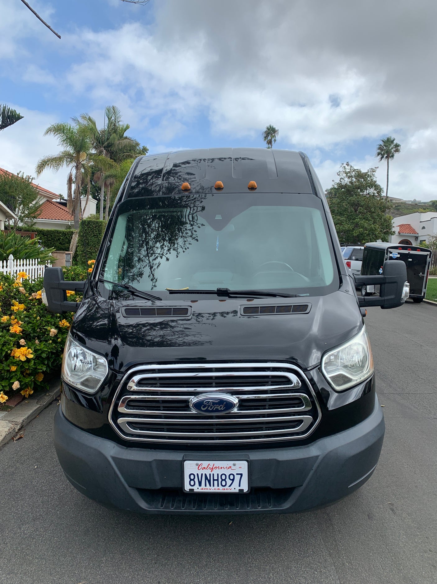Front view of a black Ford Transit van with CA plates, a common option for RV rental conversions.