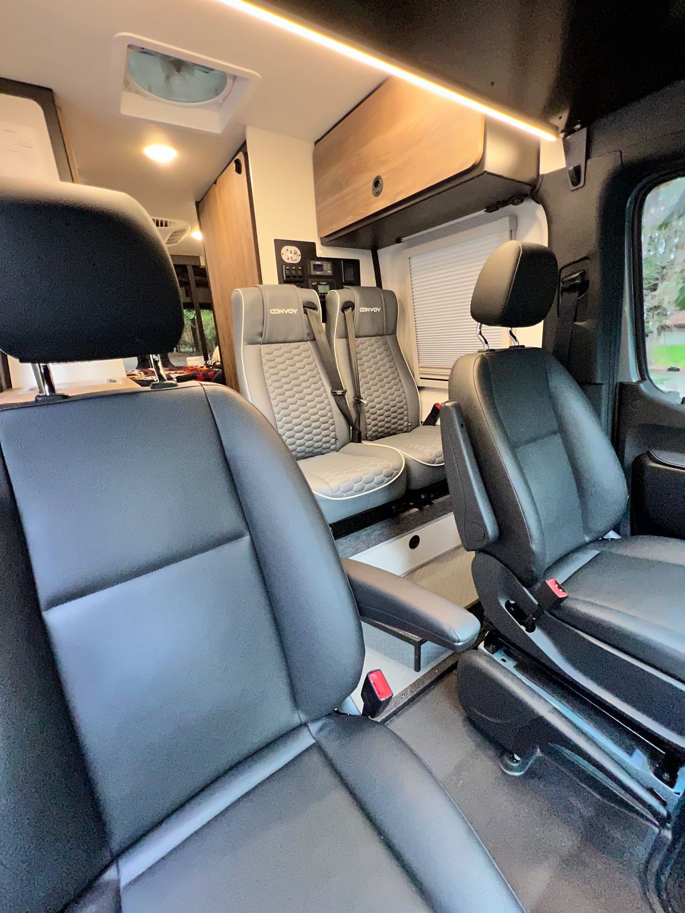  parked in a forest. Features off-road tires and a roof rack.|Explore in this custom gray RV rental camper van — photo 6