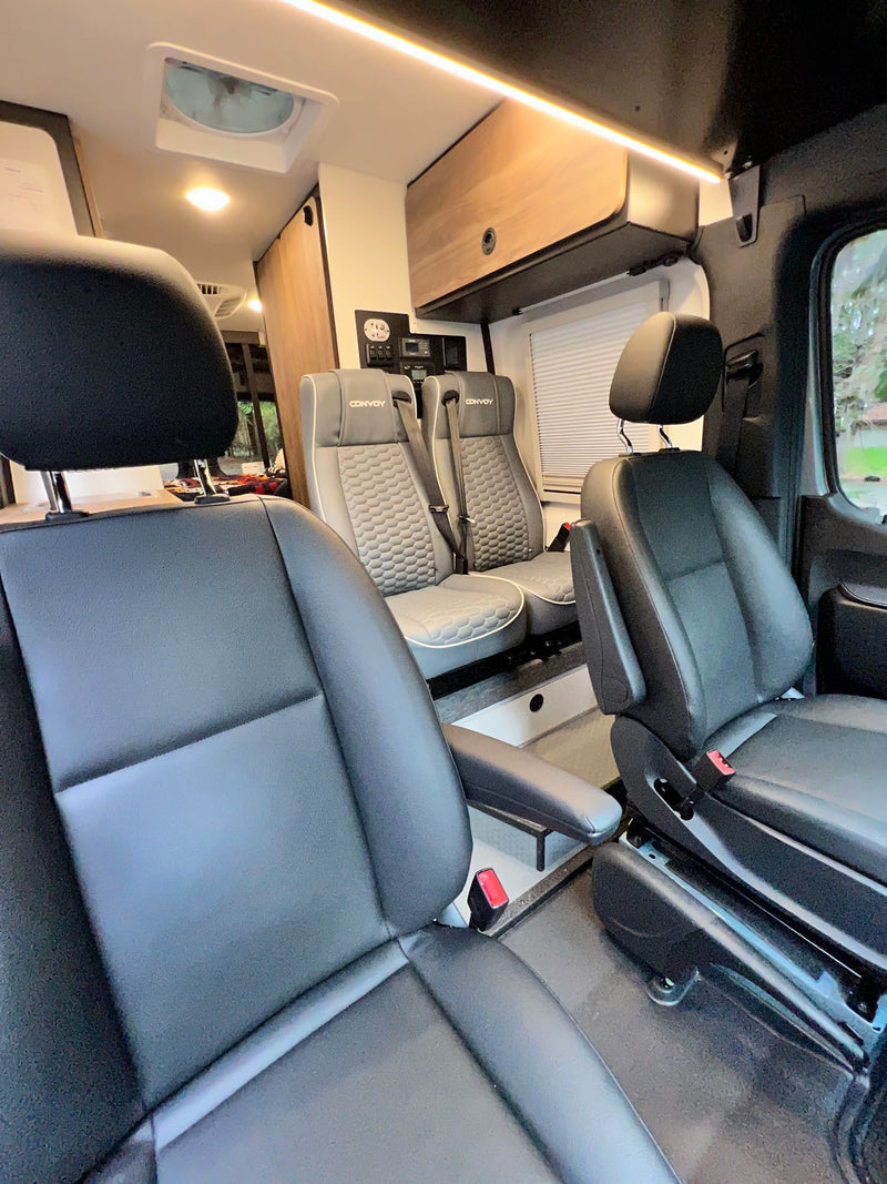 parked in a forest. Features off-road tires and a roof rack.|Explore in this custom gray RV rental camper van — photo 6