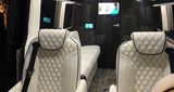 Experience our RV rental: plush white quilted seats, a lounge bed, and a TV inside this luxury van conversion.