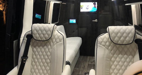 Experience our RV rental: plush white quilted seats, a lounge bed, and a TV inside this luxury van conversion.