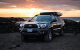 Hawaii: Toyota Tacoma with rooftop tent, parked by the ocean at sunset. A unique RV rental option for adventure travel.