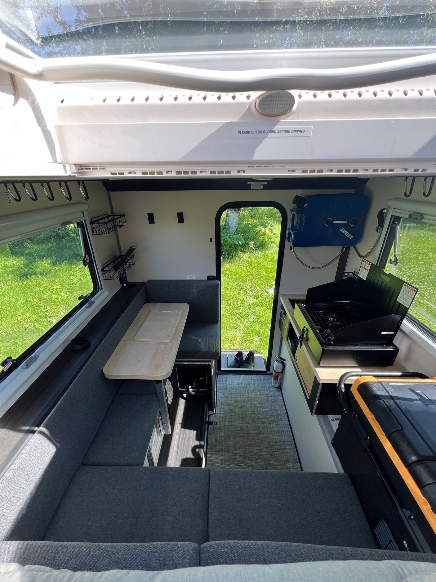 Bright rv rental interior features a U-shaped dining area, compact kitchen with stove, and outdoor access to green space.
