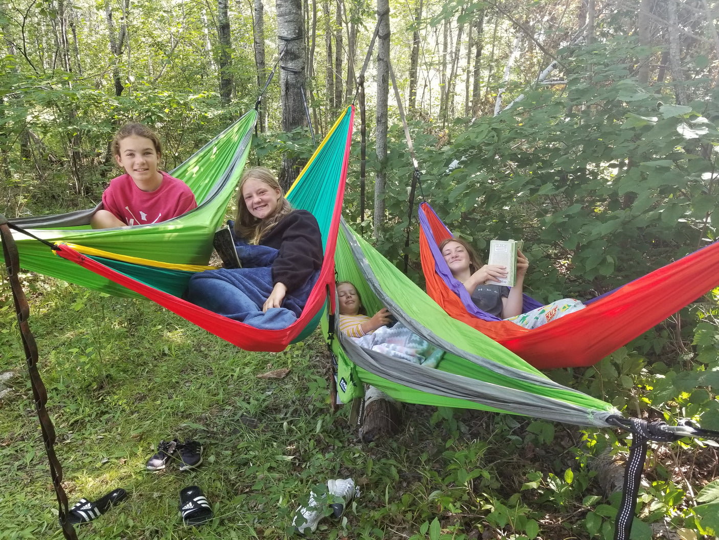 Four girls relax in vibrant hammocks among forest trees, a perfect serene moment for an **RV rental** outdoor trip.