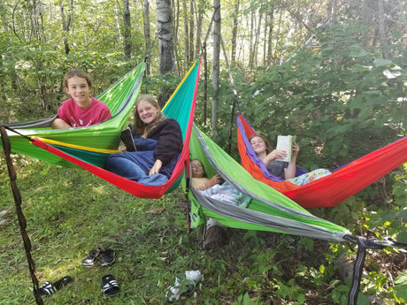 Four girls relax in vibrant hammocks among forest trees, a perfect serene moment for an **RV rental** outdoor trip.