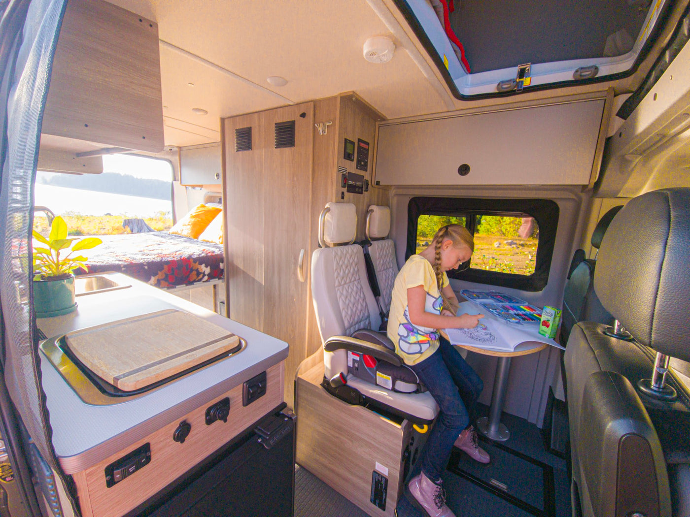  offering a screened view of a peaceful forest campsite.|An RV rental Winnebago Solis camper van on a scenic highway with snow-capped Mt. Hood in the distance.|Inside a bright RV rental — photo 7