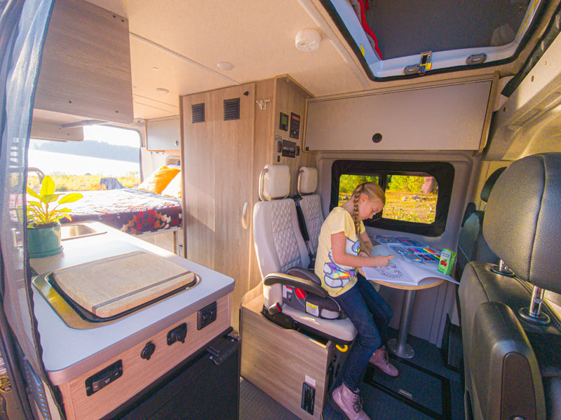  offering a screened view of a peaceful forest campsite.|An RV rental Winnebago Solis camper van on a scenic highway with snow-capped Mt. Hood in the distance.|Inside a bright RV rental — photo 7