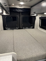 Comfortable RV rental interior featuring a spacious bed, overhead storage cabinets, and rear windows, ready for your trip.