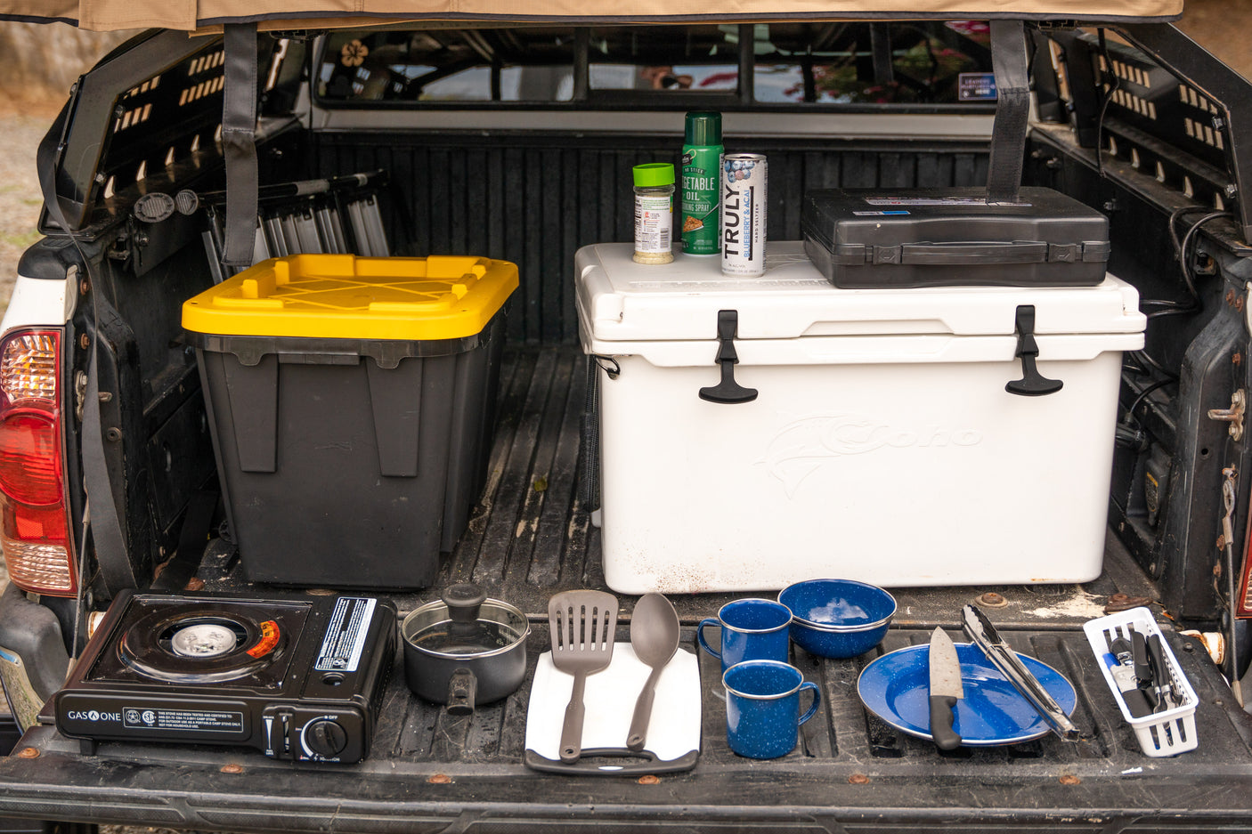 RV rental ready! Truck bed packed with camp kitchen setup, including stove, cooler, and cooking essentials for adventures.