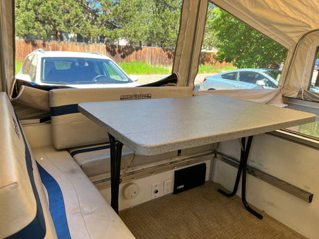 Inside a Quicksilver RV rental: cozy dinette area with table, seats, and view of parked cars.