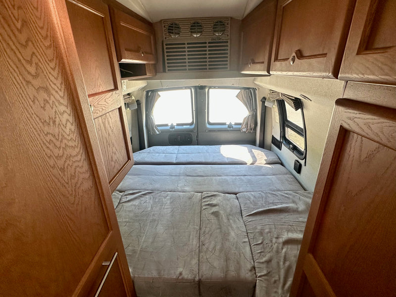 Step inside this inviting RV rental with a comfy modular bed, overhead cabinets, and bright rear windows. Your road trip awaits! — photo 7