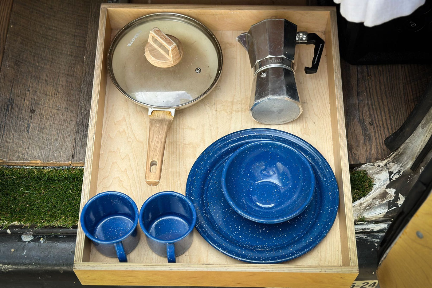 Compact kitchen setup in an RV rental: pan, Moka pot, blue mugs, plates. Ready for camping meals!