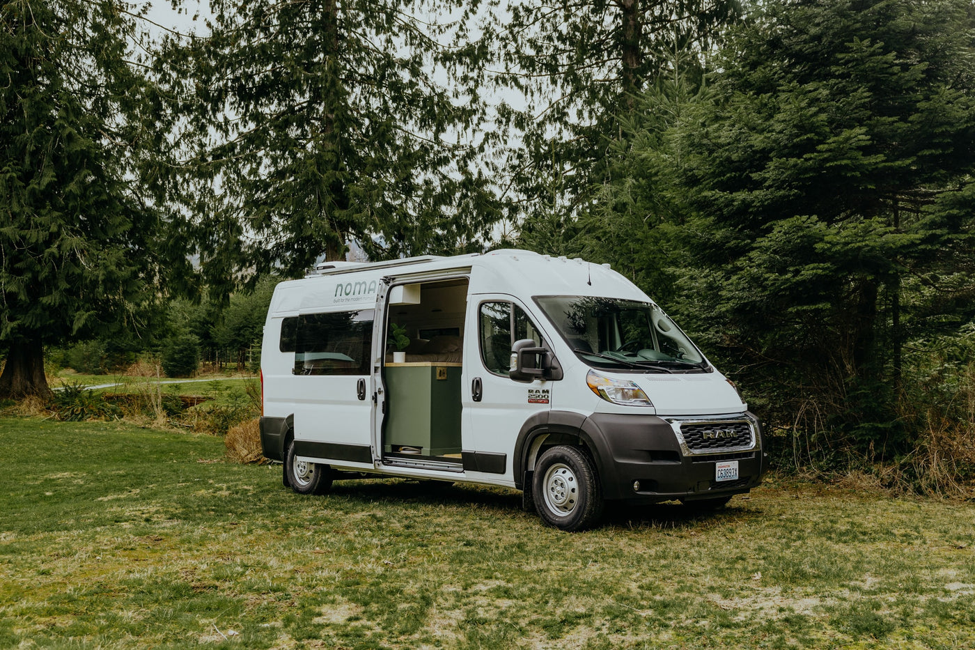 Explore nature in this white rv rental camper van, parked amidst lush green trees and grass. A perfect outdoor getaway. — photo 16