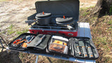 Outdoor cooking station for your RV rental: a red Everest stove, two pots, and a full set of organized cooking utensils.