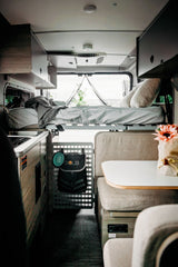 Cozy RV rental interior with a raised bed, kitchen, and dinette. Perfect for road trips and adventurous travel.