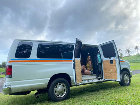 This RV rental campervan, with a smiling woman inside, offers adventure and van life travel.