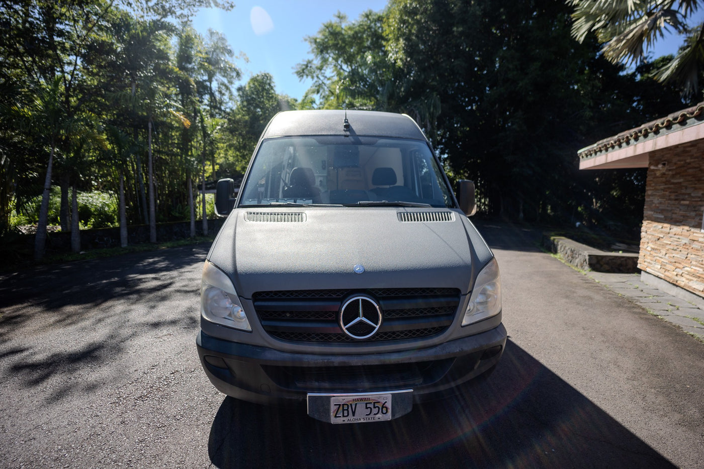 Grey Mercedes Sprinter van, an RV rental, parked on an asphalt drive with tropical trees and a building. — photo 13