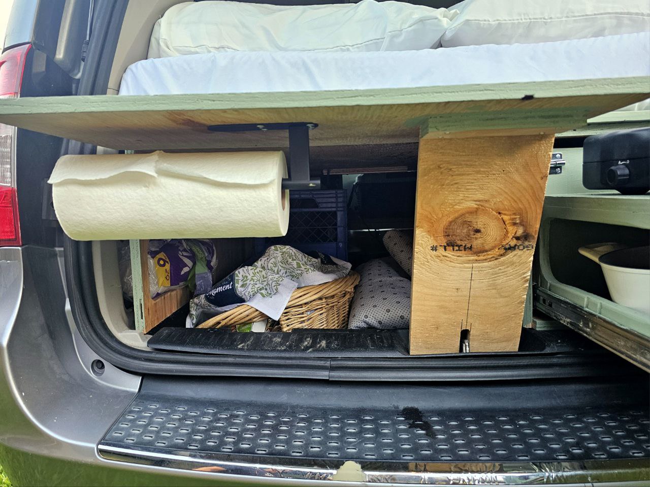 Optimized RV rental space: Back of a converted van/SUV with bed platform, paper towels, and storage for camping ease. — photo 9