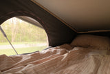 Cozy RV rental bed with striped bedding. Enjoy a tranquil nature view, perfect for camping & travel.
