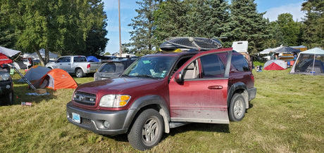 Outdoor camping scene: an SUV, tents, and a classic RV rental camper van in a grassy campground.