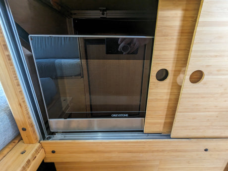 Greystone microwave in smart bamboo cabinetry with sliding panels, maximizing space in this RV rental's kitchen.