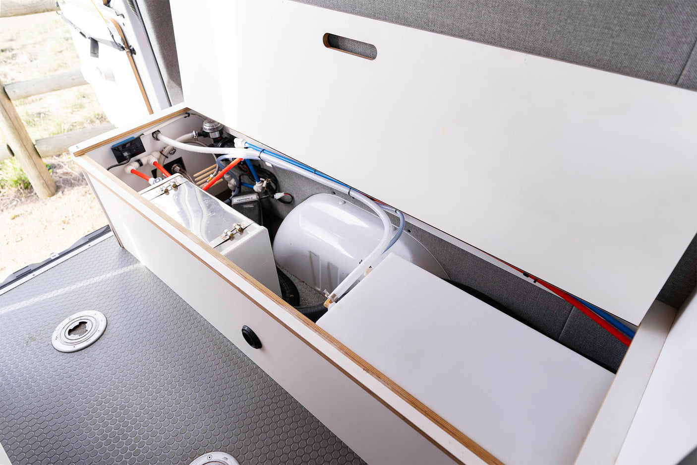 RV rental water system: Inside a camper van, view its fresh water tanks, plumbing, and pump essentials for travel.