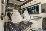 Luxurious RV rental interior features cream leather seats, glossy wood accents, and soft ambient lighting for ultimate comfort.